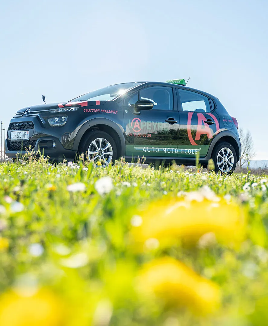 Voiture double commande de l'auto-école Lapeyre dans un champ de fleurs