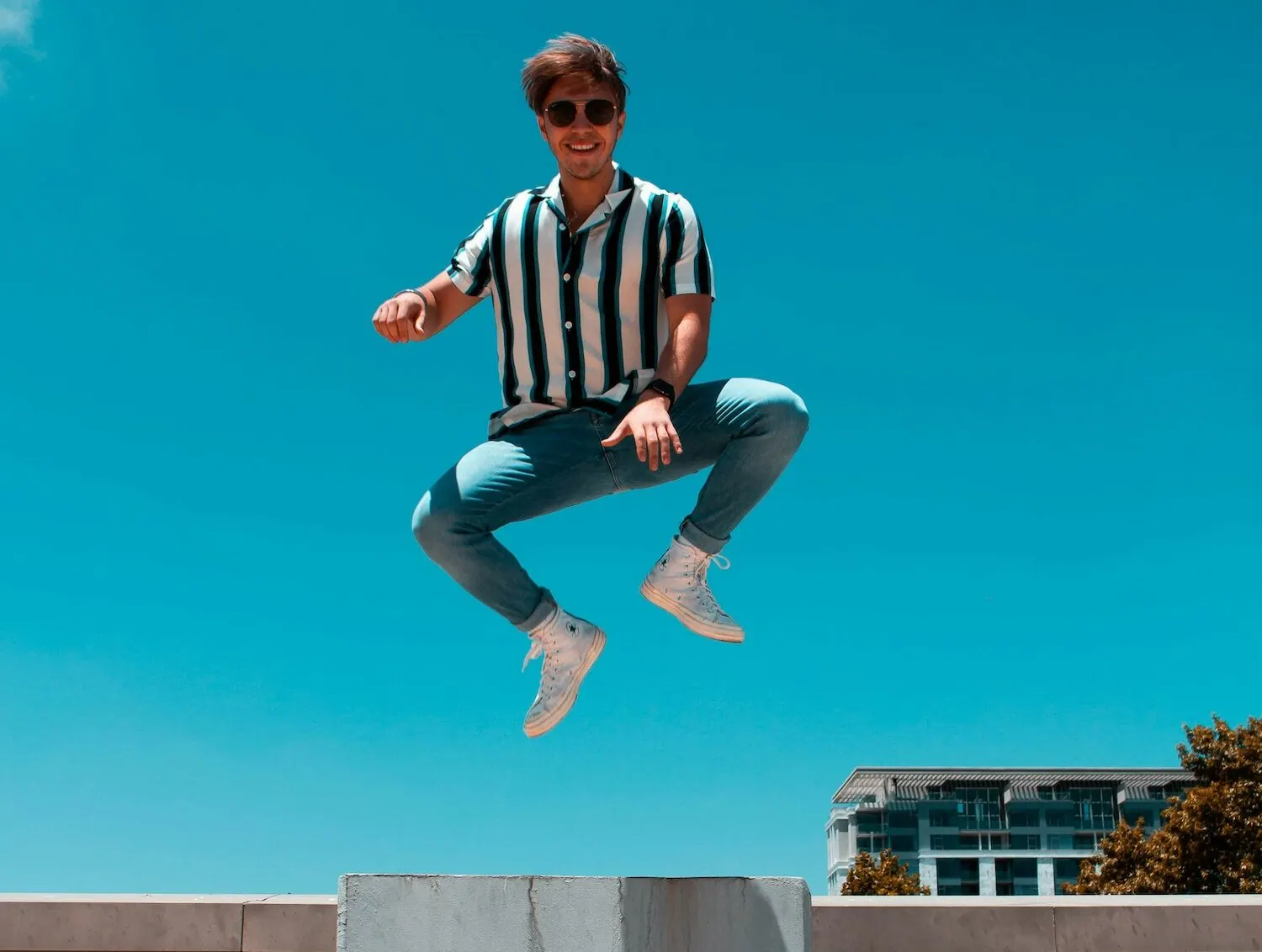 Jeune homme sautant de joie devant un ciel bleu
